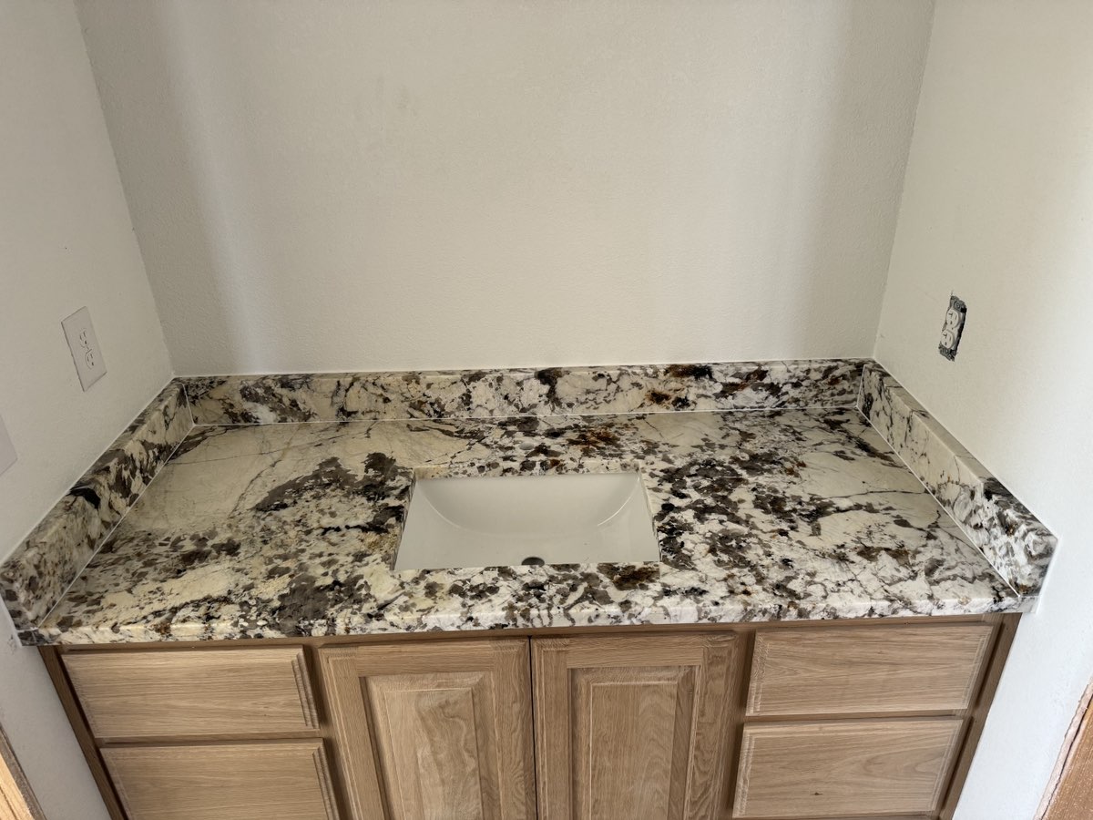 Creme Delicataus granite countertops with white shaker cabinets and custom dog wash area — Central Texas