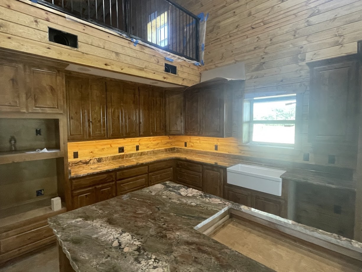 River Bordeaux granite kitchen with white cabinets and stainless farmhouse sink