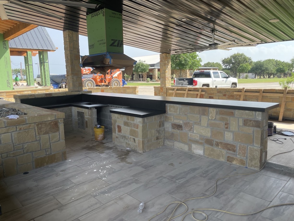 Black granite outdoor kitchen countertops on limestone block walls — custom outdoor living Central Texas