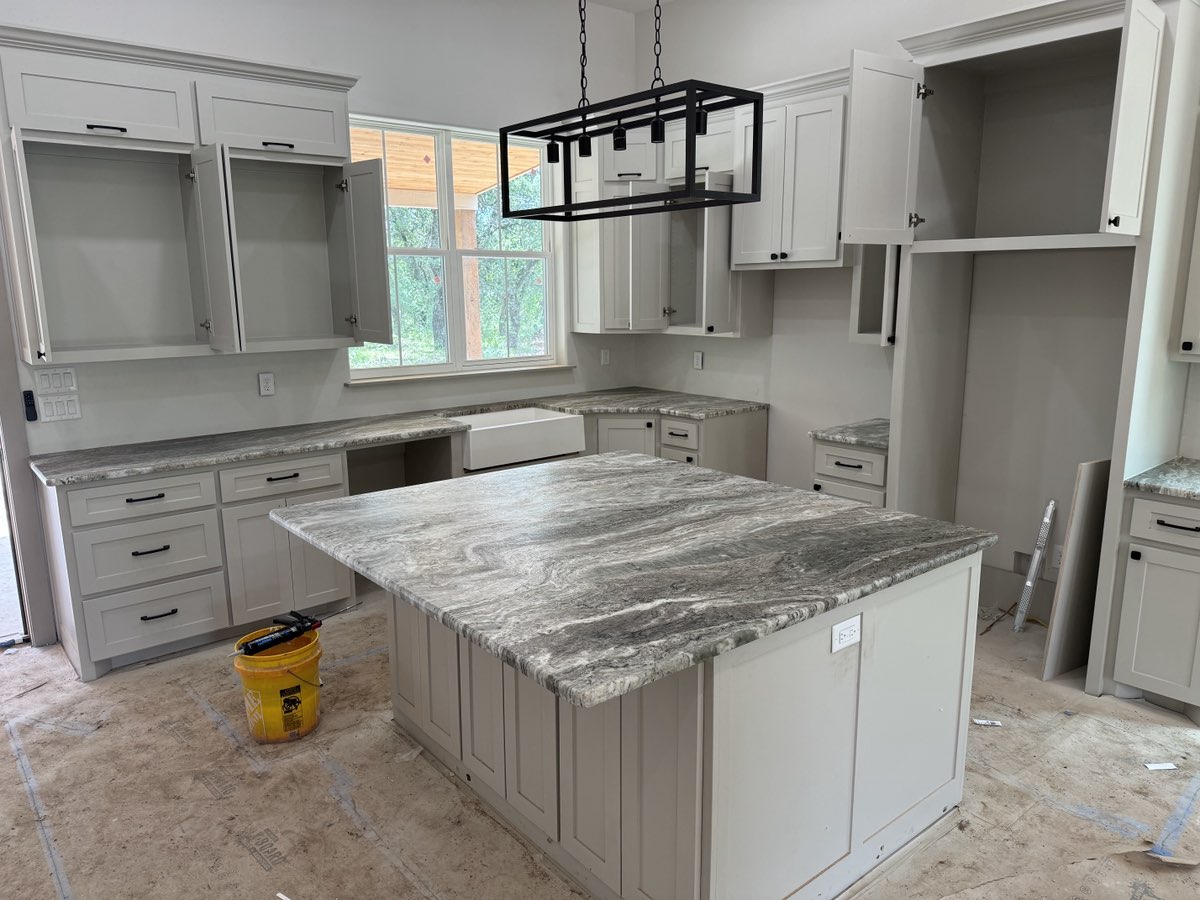 Brown Fantasy marble kitchen island and perimeter counters with grey shaker cabinets and farmhouse sink — new construction Central Texas