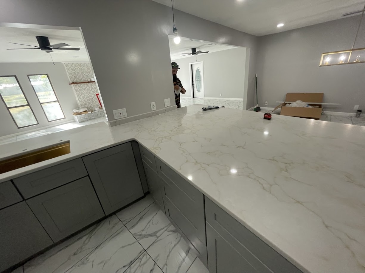 Milan Gold quartz large kitchen peninsula on grey shaker cabinets with marble tile floor — Central Texas installation