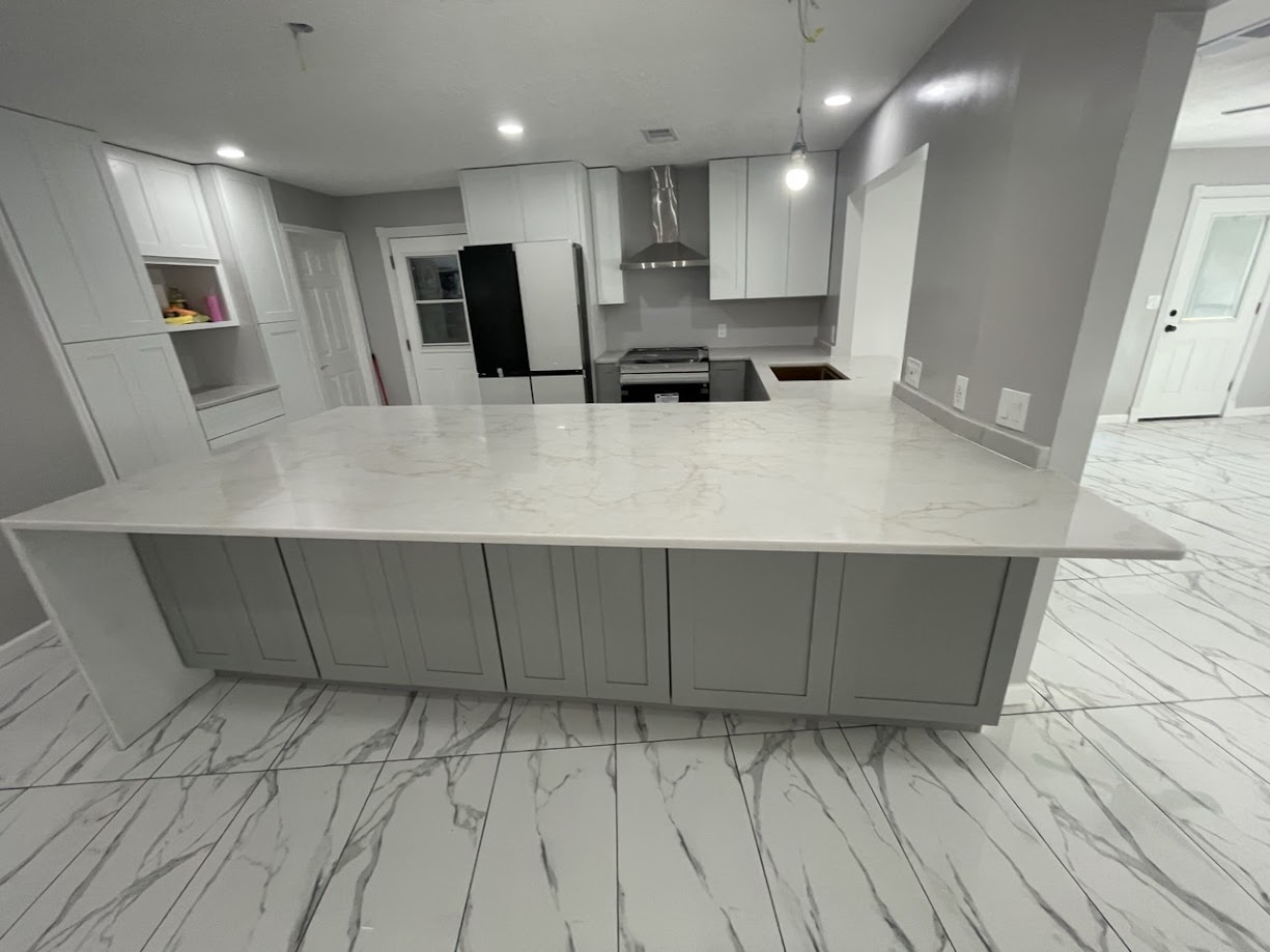 Milan Gold quartz wide view of full kitchen peninsula with white upper cabinets and marble tile — Heart of Texas Granite & Marble