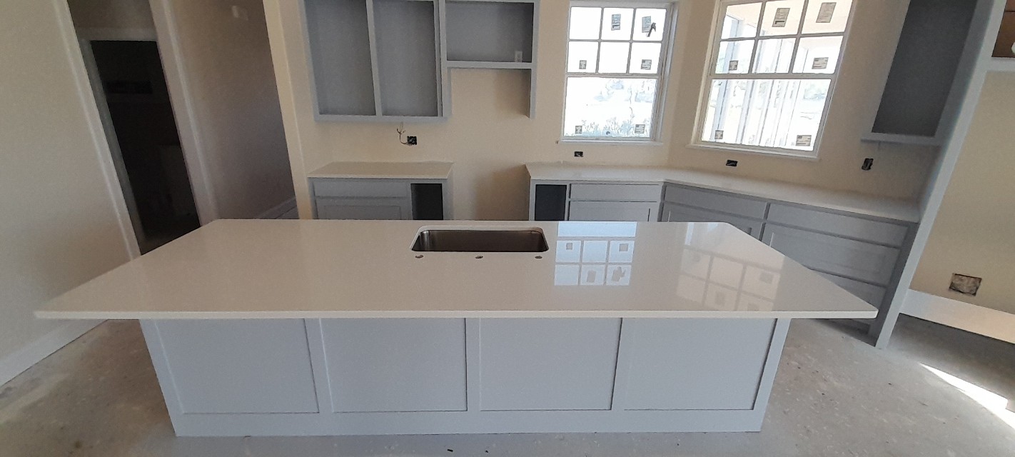 Pure white quartz kitchen island with undermount sink on light grey cabinets — new construction Central Texas