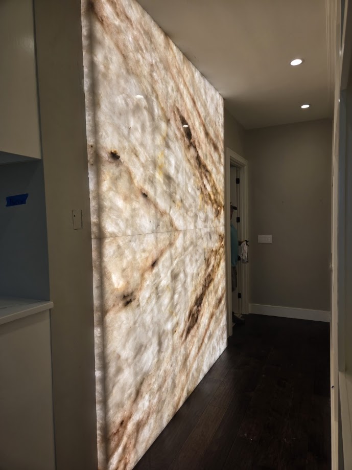 Cristallo quartzite backlit accent wall panel with glowing cream and amber tones — luxury Central Texas home