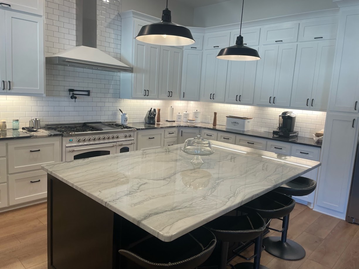 Infinity White quartzite kitchen wide angle view with white shaker cabinets industrial pendants and dark island — Central Texas installation