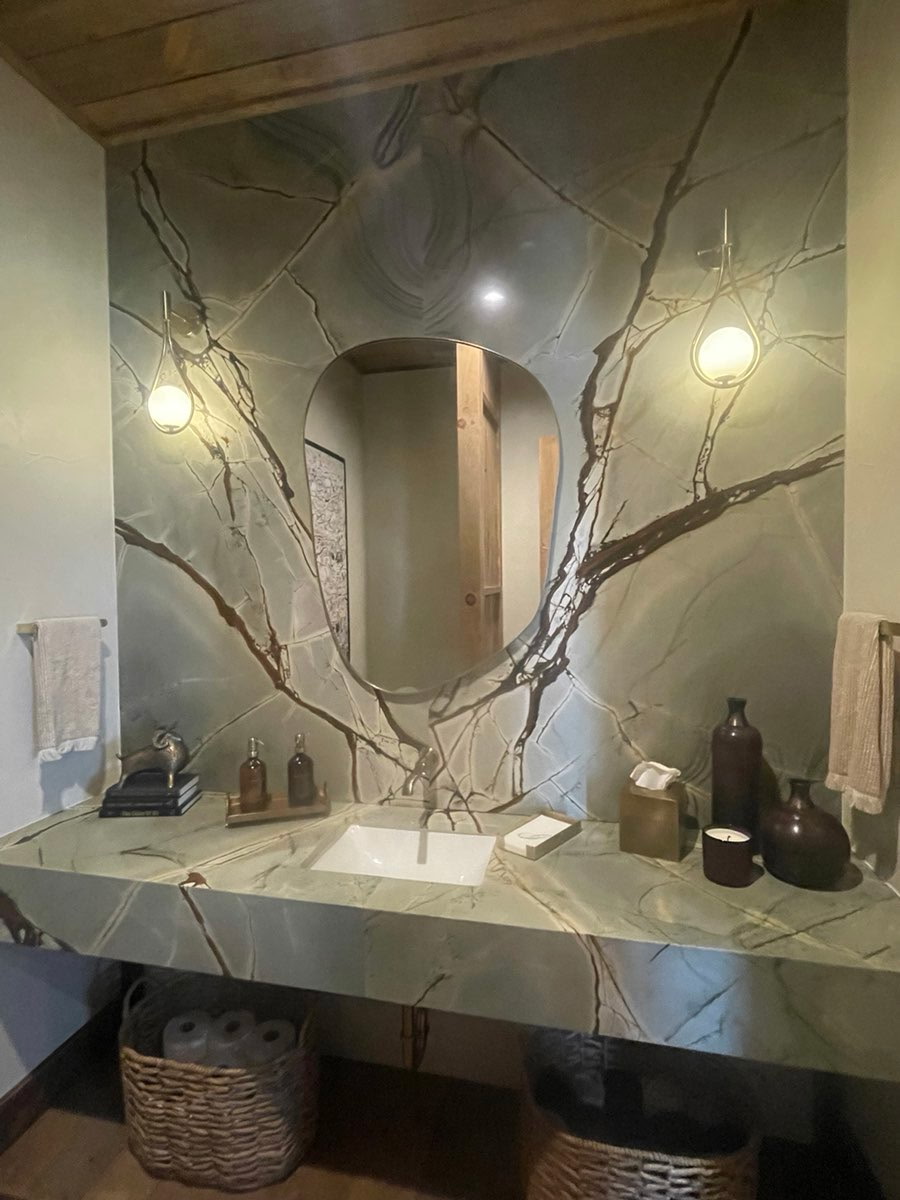 Sauipe quartzite full bathroom wall cladding and floating vanity with dramatic green grey branch-like veining — round oval mirror spa design Central Texas