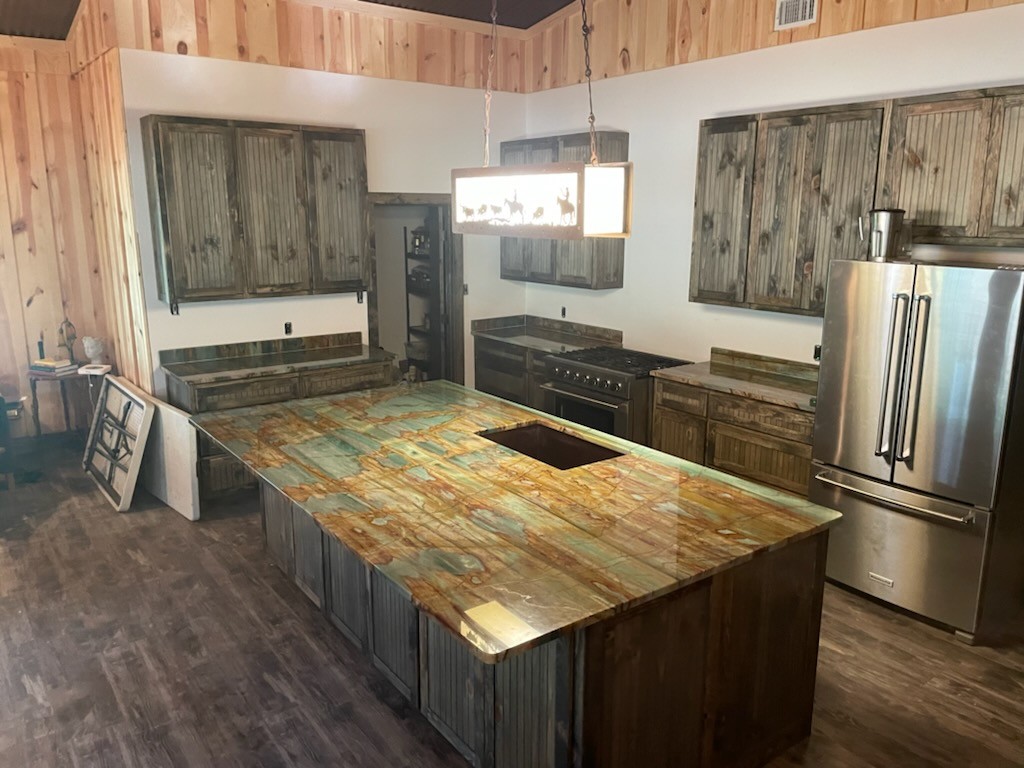 Sauipe quartzite full ranch kitchen wide view with teal gold quartzite island and perimeter — distressed cabinets cedar walls Central Texas
