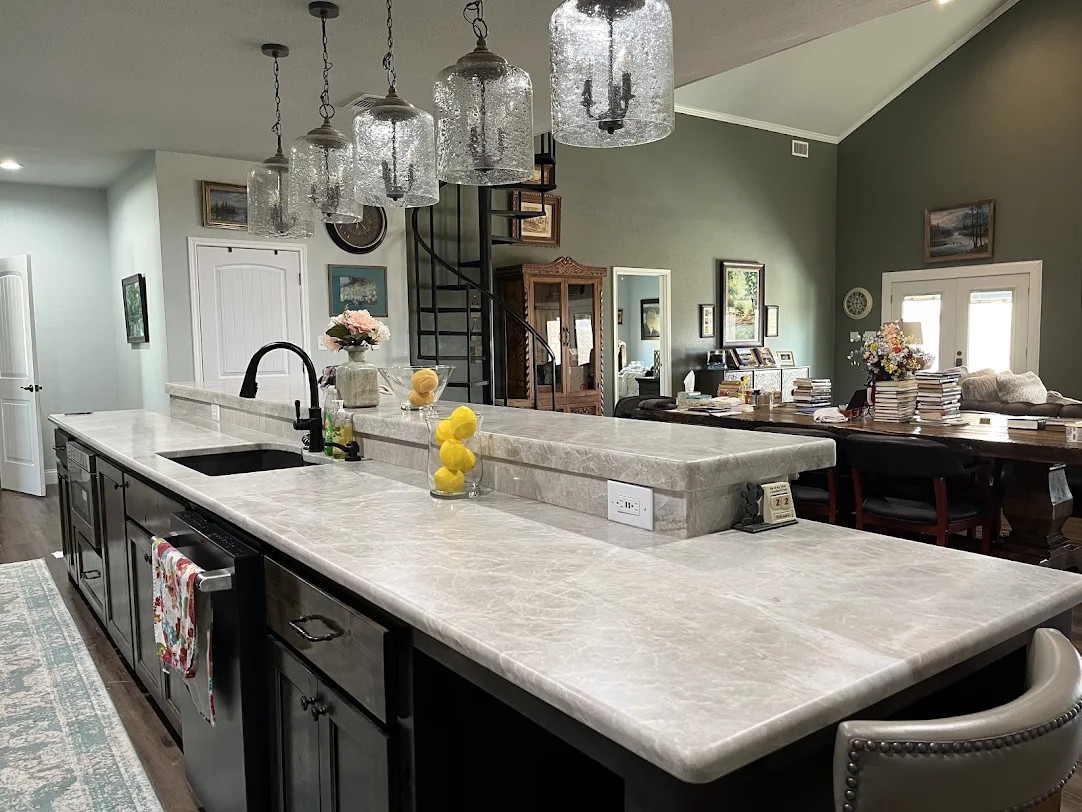 Silver grey quartzite kitchen island with raised bar and black farmhouse sink on dark espresso cabinets — Central Texas